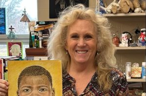 Mrs. Concascia alongside a portrait created for the Memory Project.