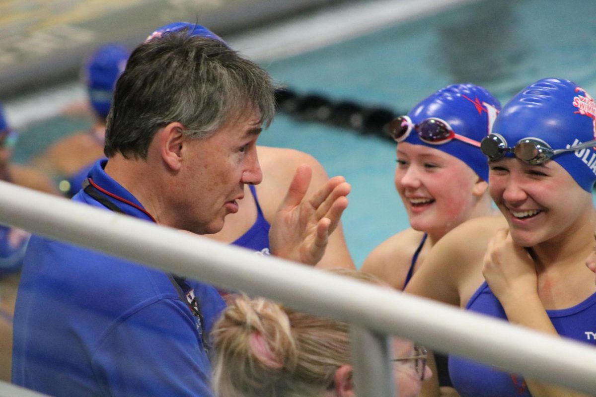 Coach Gathy talking to swimmers at a meet. 